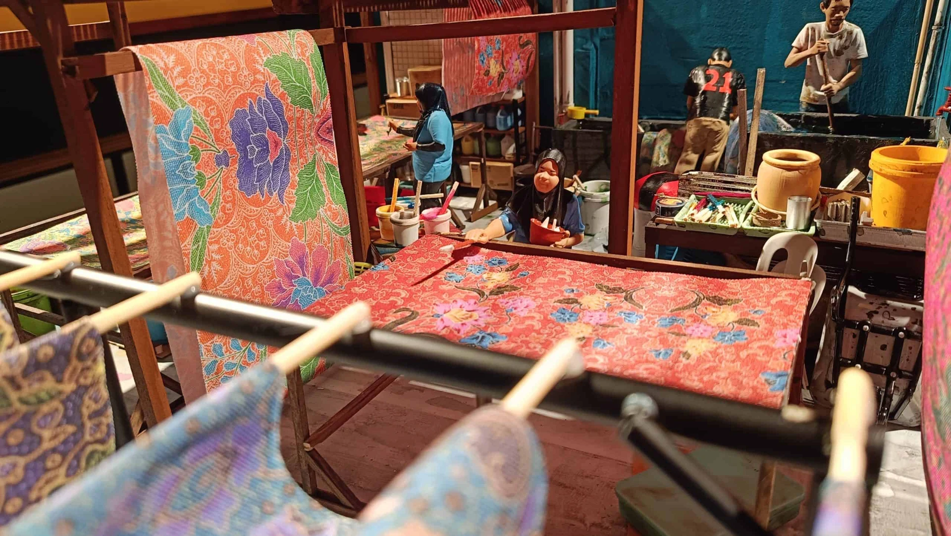 Miniature batik workshop with patterned fabrics and tiny craftspeople